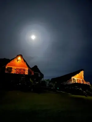 a night view of a barn with the moon in the sky at Margarita Ecovillage in Miches