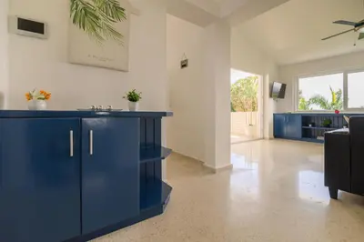 a kitchen with blue cabinets and a living room at Mango y Jobo - Relaxed Mountain & Sea Panoramic view - 10mins drive to beach and city in San Felipe de Puerto Plata
