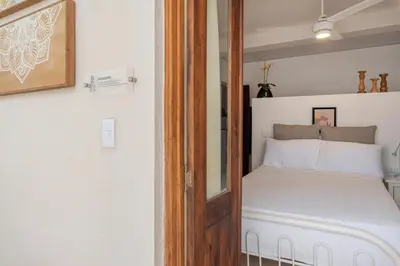 a small bedroom with a bed with white sheets at 3 Studios at Casa Areito in Santo Domingo