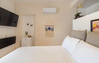 a bedroom with a white bed and a flat screen tv at 3 Studios at Casa Areito in Santo Domingo