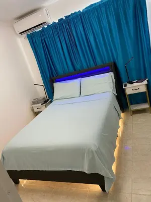 a bedroom with a large bed with a blue curtain at Nice and Breezy Apartment in Santiago de los Caballeros
