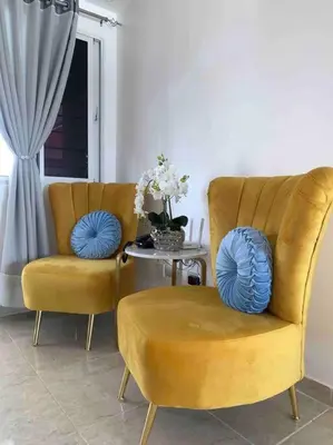 a living room with two chairs and a table with blue pillows at Nice and Breezy Apartment in Santiago de los Caballeros