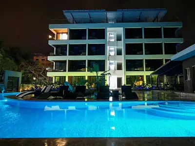 a swimming pool in front of a building at night at Surf One in Sosúa