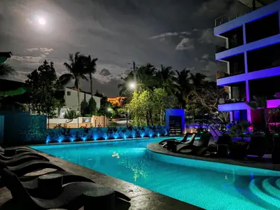 a swimming pool at night with chairs and a building at Surf One in Sosúa