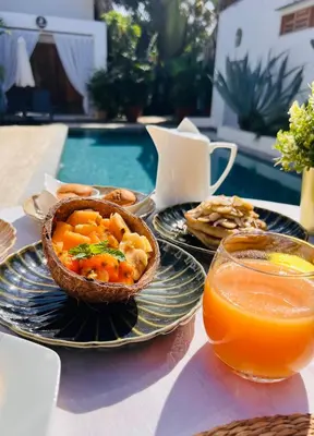 a table with a bowl of food and a glass of orange juice at Leeloo Boutique Hotel in Las Terrenas