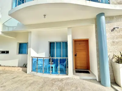 a house with a balcony with a wooden door at Elegante Apartamento A 100 mts la playa de los Minos RSJ in Río San Juan