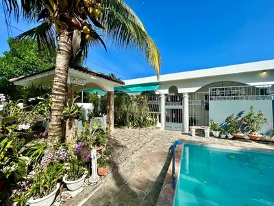 a house with a palm tree and a swimming pool at Casa Tipo Villa, Piscina, Playas De RSJ a 4 min in Río San Juan