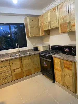 a kitchen with wooden cabinets and a stove top oven at Apartamento con agua caliente para 9 personas in La Ureña