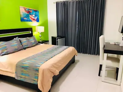 a bedroom with a bed and a desk and green walls at Dpravia Hotel SRL in Baní