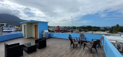 a balcony with chairs and a table on a roof at Residencial Doña Gloria 2 in San Felipe de Puerto Plata