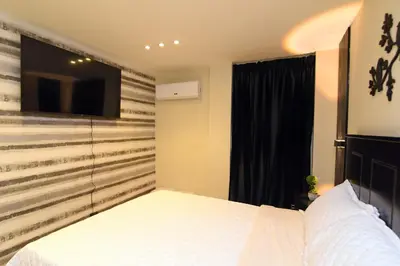 a bedroom with a bed and a tv on a wall at Solmi Rooms in Calero