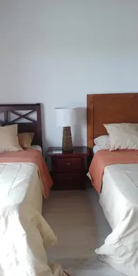 a bedroom with two beds and a night stand at Apartamentos Essential Life con playa y piscina in Punta Cana