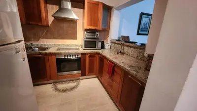 a kitchen with wooden cabinets and a stove top oven at Apartamentos Essential Life con playa y piscina in Punta Cana