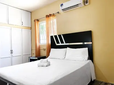 a bedroom with a large bed with white sheets at Guest House A&H in Boca Chica