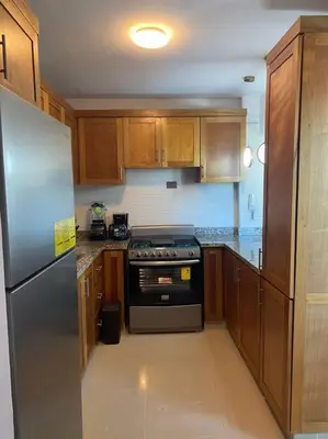 a kitchen with wooden cabinets and a stainless steel refrigerator at Luxury Penthouse Santo Domingo W in Santo Domingo