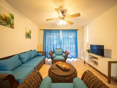 a living room with a blue couch and a tv at 2br Caribbean Condo In Cabarete Center in Cabarete