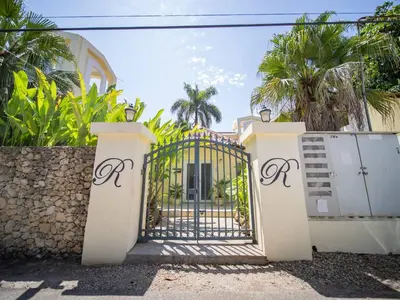 a gate in front of a house with palm trees at 2br Caribbean Condo In Cabarete Center in Cabarete