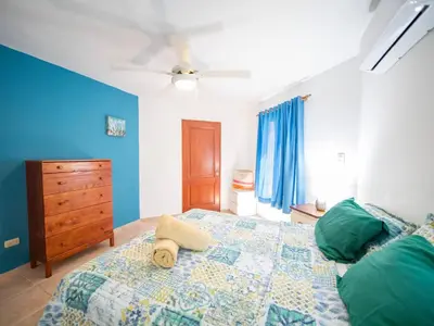 a bedroom with a bed and a dresser and blue walls at 2br Caribbean Condo In Cabarete Center in Cabarete