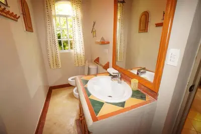 a bathroom with a sink and a mirror and a toilet at Villa Playa Bonita, Pool, Tropical Gardens in Las Terrenas