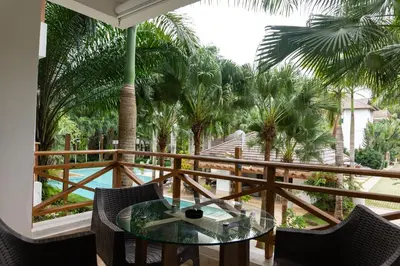 a balcony with a glass table and some palm trees at Departamento en las Terrenas a pie de Playa in Las Terrenas
