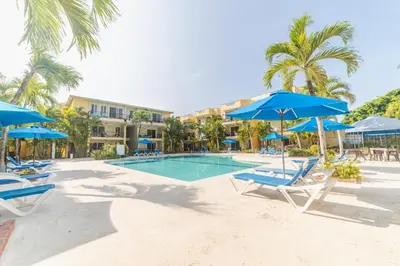 a swimming pool with blue umbrellas and chairs at Garden Condos 39, Luxury Apartment In Sosua Town in Sosúa