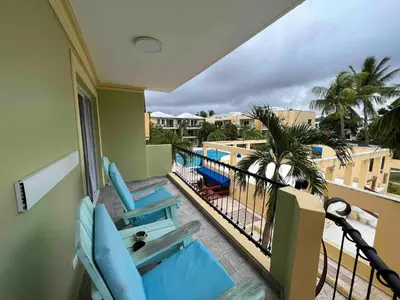 a balcony with blue chairs and a view of the pool at Garden Condos 39, Luxury Apartment In Sosua Town in Sosúa