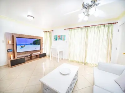 a living room with a television and a white couch at Garden Condos Apt 30 - Lovely 1br Condo W Pool in Sosúa