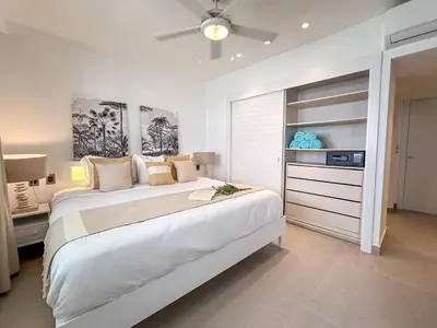 a white bedroom with a large bed and a ceiling fan at Beach Homes Punta Cana in Punta Cana