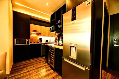 a kitchen with black cabinets and a stainless steel refrigerator at RoyalSuite 1BDR-Poll-Gym-Saune-g17 in Santo Domingo