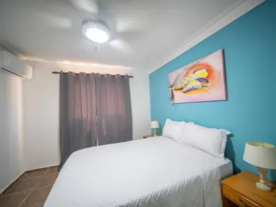 a bedroom with a white bed and a blue wall at Garden Condos 10, 2br Apt In Sosua Strip in Sosúa
