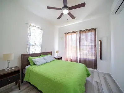 a bedroom with a green bed and a ceiling fan at Amazing 2br Villa Near Surfing Beaches in Cabarete