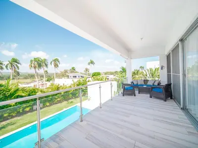 a balcony with a view of a pool and palm trees at Amazing 2br Villa Near Surfing Beaches in Cabarete