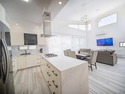 a kitchen with white cabinets and a living room at Amazing 2br Villa Near Surfing Beaches in Cabarete