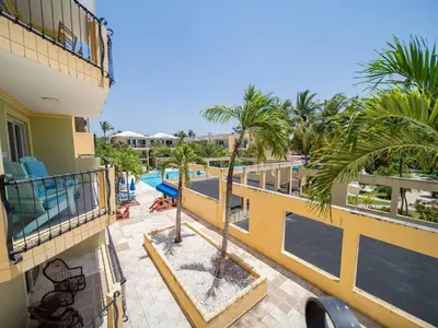 an apartment balcony with a pool and palm trees at Garden Condos 40, 1br Apt In Sosua Strip Guest Ok in Sosúa