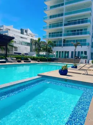 a swimming pool in front of a large building at Serenity by the Sea Oceanfront Apartment in San Pedro de Macorís