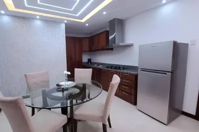 a kitchen with a glass table and a refrigerator at Hermoso apartamento con vista al mar y la ciudad in La Romana