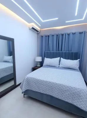 a bedroom with a blue bed and a mirror at Hermoso apartamento con vista al mar y la ciudad in La Romana