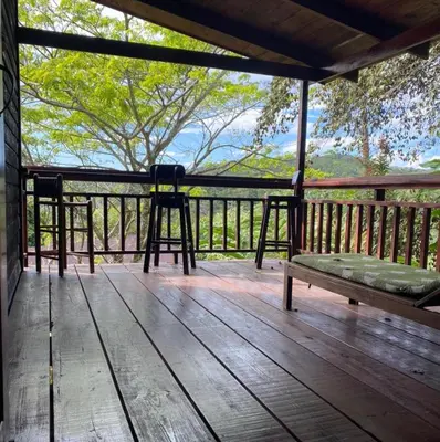 a wooden porch with a bench and a stool on it at Rancho Fernandez in Jarabacoa