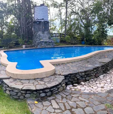 a swimming pool with a stone retaining wall around it at Rancho Fernandez in Jarabacoa