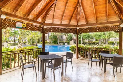 a patio with tables and chairs and a swimming pool at Punta Cana 1-Bed Apt Sleeps 4 with Pool & Hot Tub in Punta Cana