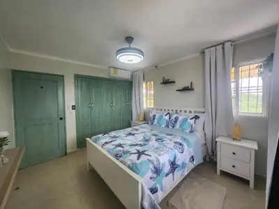 a bedroom with a bed with a blue and white comforter at Penthouse Apartment with Bay and Mountain Views, Rooftop BBQ, AC, Fast WiFi, Near Saladilla Beach, Barahona in Santa Cruz de Barahona