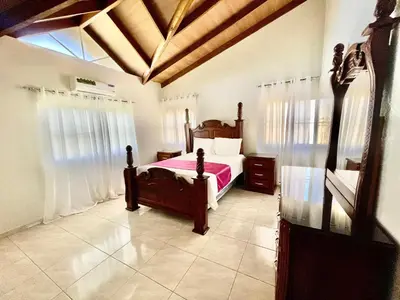 a bedroom with a bed with a pink comforter at Encantadora Terraza de Brisas Frescas in Jarabacoa