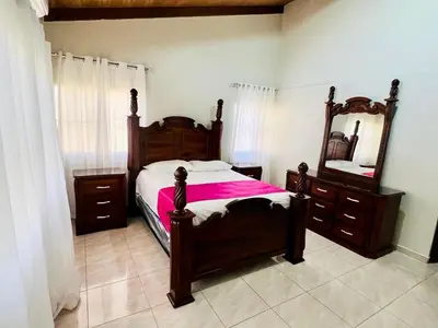 a bedroom with a wooden bed with a mirror and dresser at Encantadora Terraza de Brisas Frescas in Jarabacoa