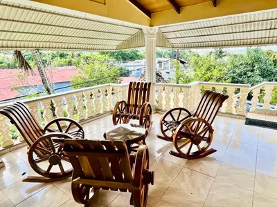 a porch with four rocking chairs and a table at Encantadora Terraza de Brisas Frescas in Jarabacoa