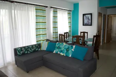 a living room with a gray couch with blue pillows at Apartment in Cadaques Caribe in Bayahibe
