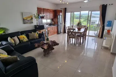 a living room with a couch and a table and a kitchen at 2 Bedroom Pool Villa in Gated Encuentro Residences by Palm Hills Real Estate in Cabarete