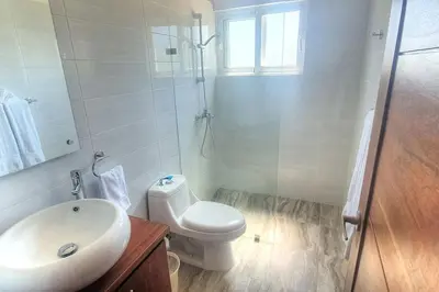 a white bathroom with a toilet and a sink at 2 Bedroom Pool Villa in Gated Encuentro Residences by Palm Hills Real Estate in Cabarete