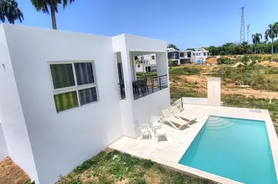 a villa with a swimming pool and a house at 2 Bedroom Pool Villa in Gated Encuentro Residences by Palm Hills Real Estate in Cabarete