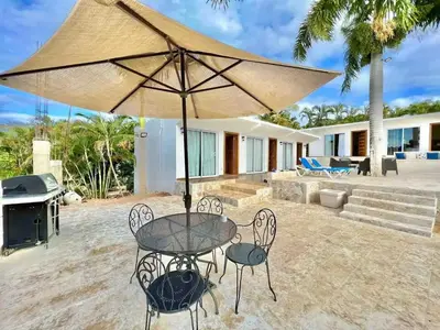 a patio with a table and chairs and an umbrella at Exclusive Paradise Palms Villa in Sosúa