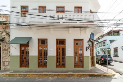 a white building with wooden doors on a street at Empyrean Art Deco in Santo Domingo